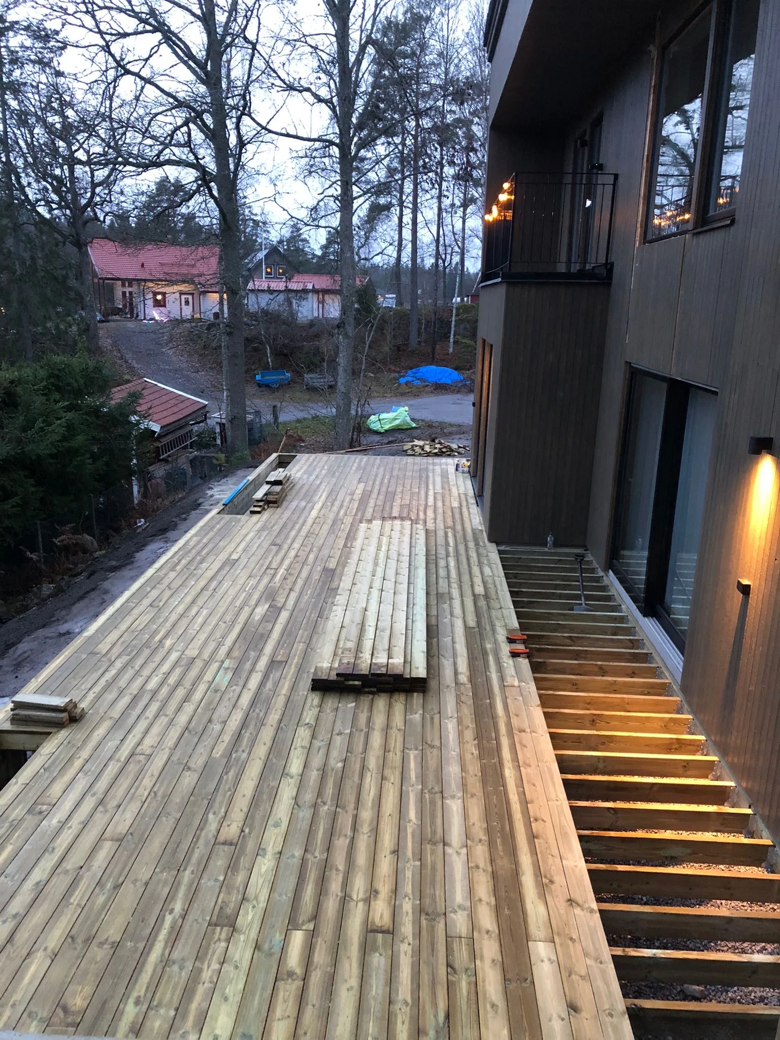 Uteplats med trädeck i nybyggnation, med byggmaterial i bakgrunden