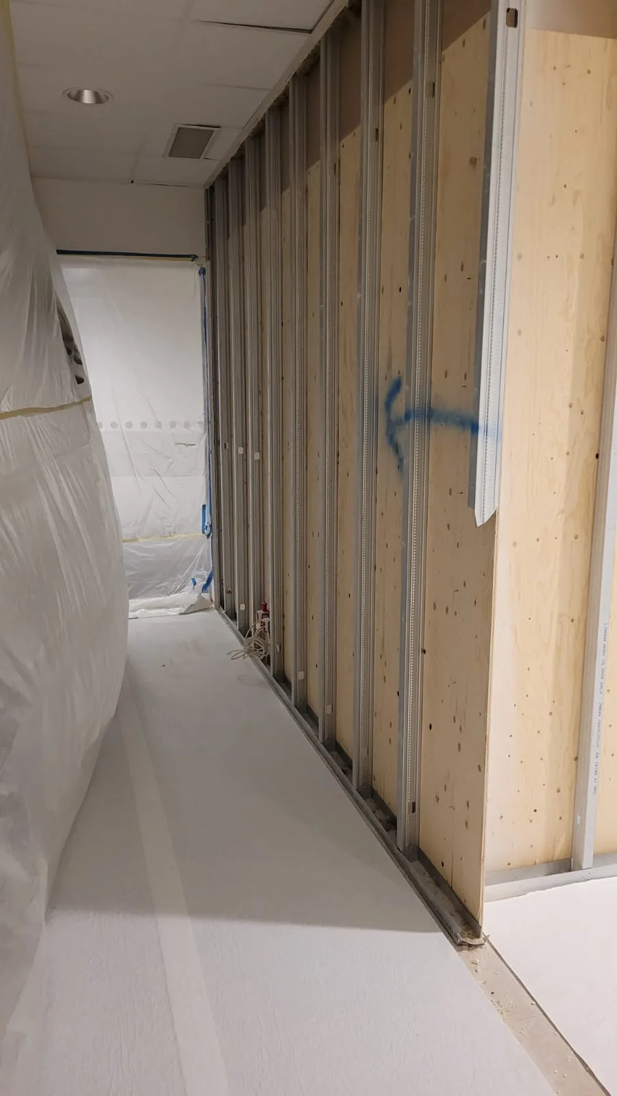Renoveringsarbete med plastöverdrag och väggstommar i en byggnadsinteriör
