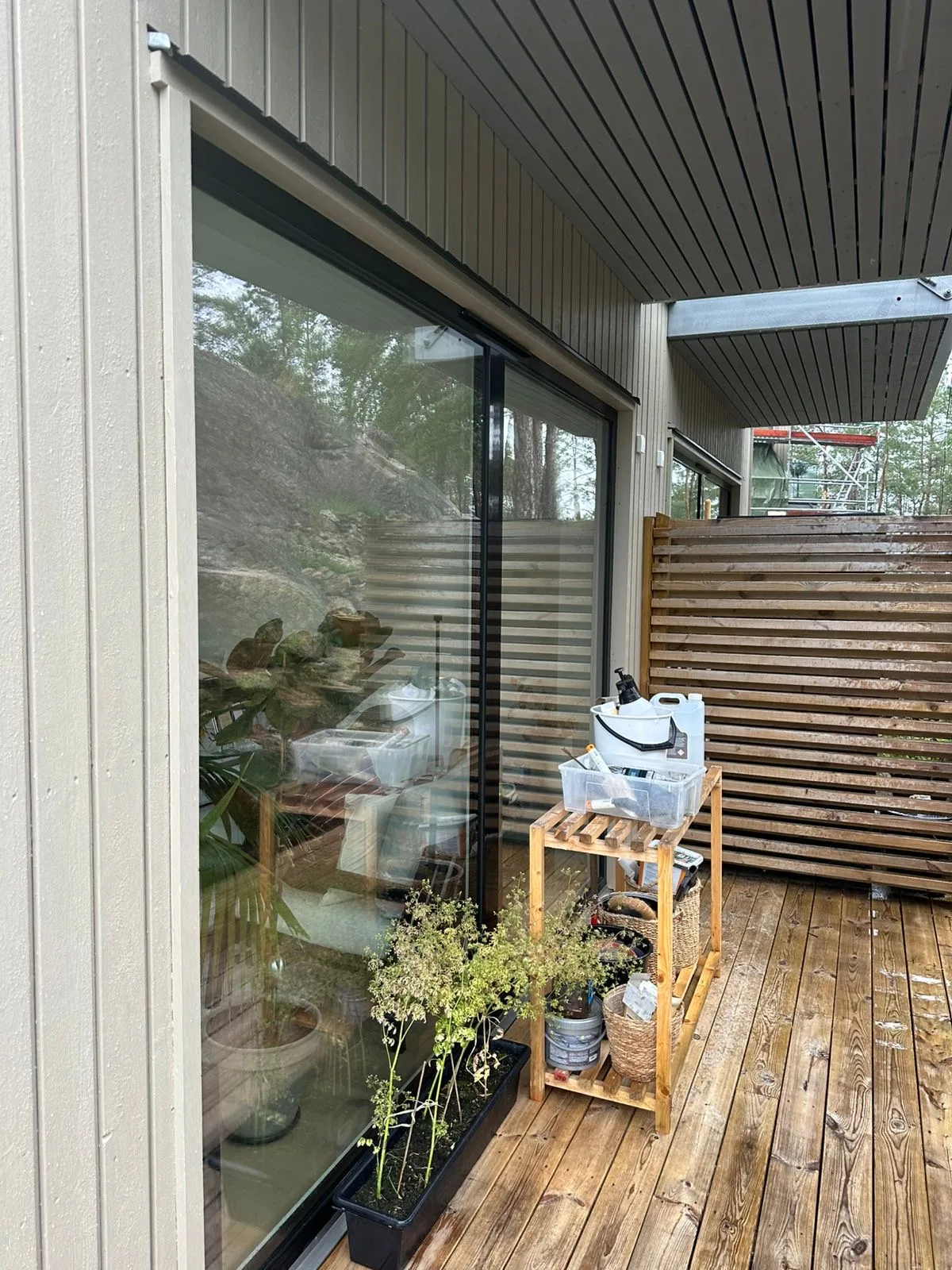 Modernt träterrass med stor glasdörr och metalltak