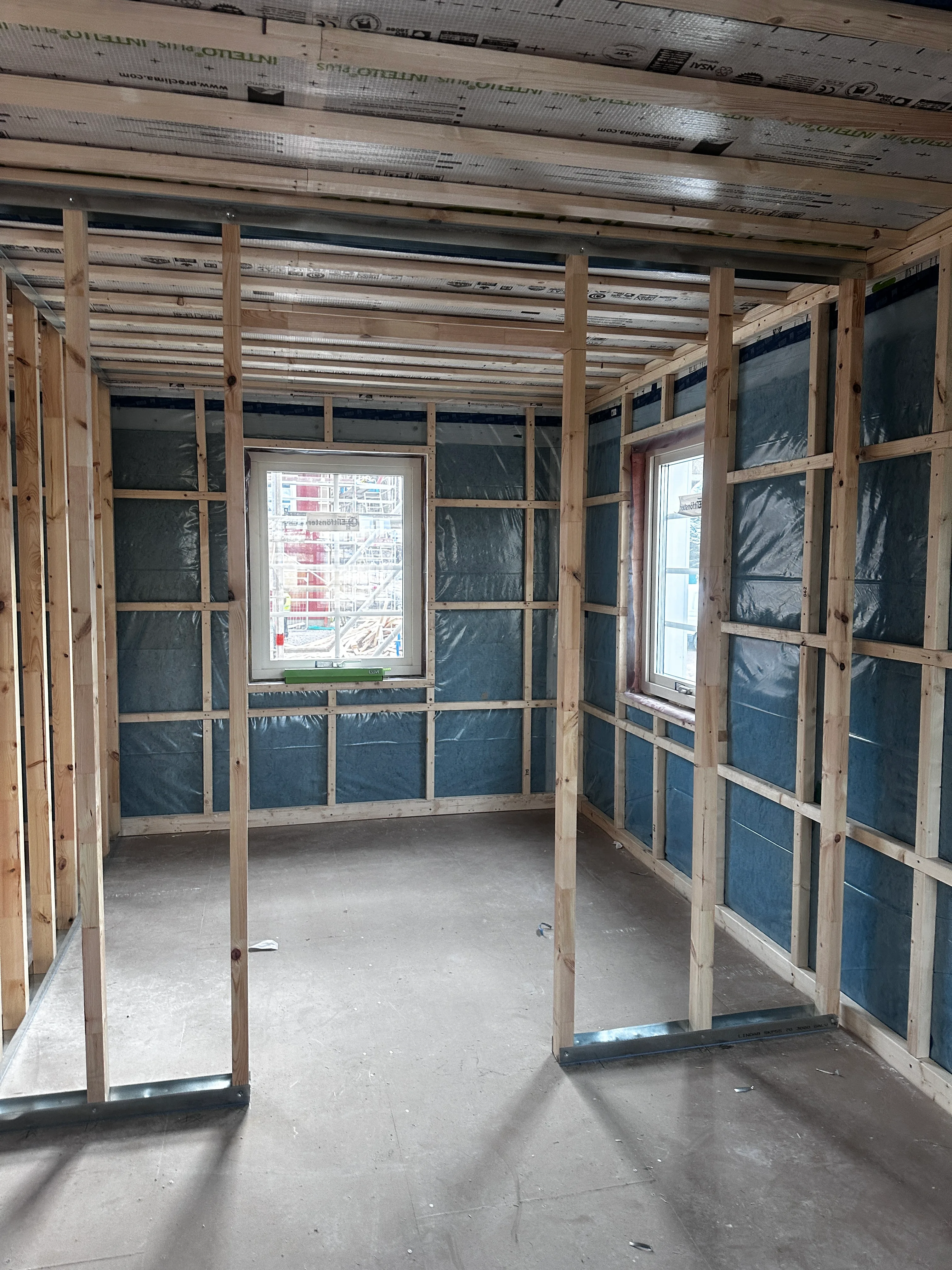 Inre av ett byggprojekt med träväggar och fönster, förberett för renovering