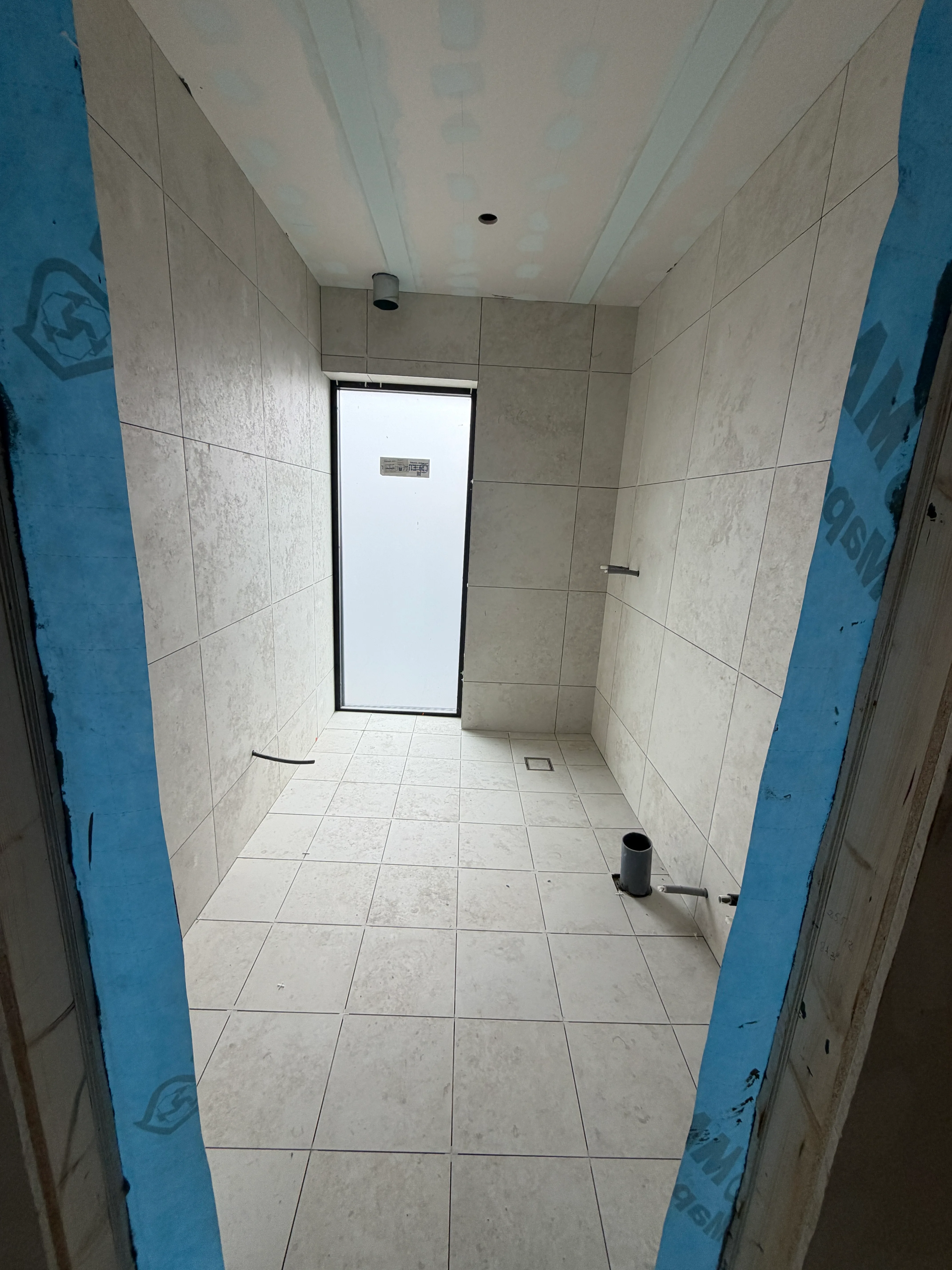 Badrum under renovering med vita kakelplattor