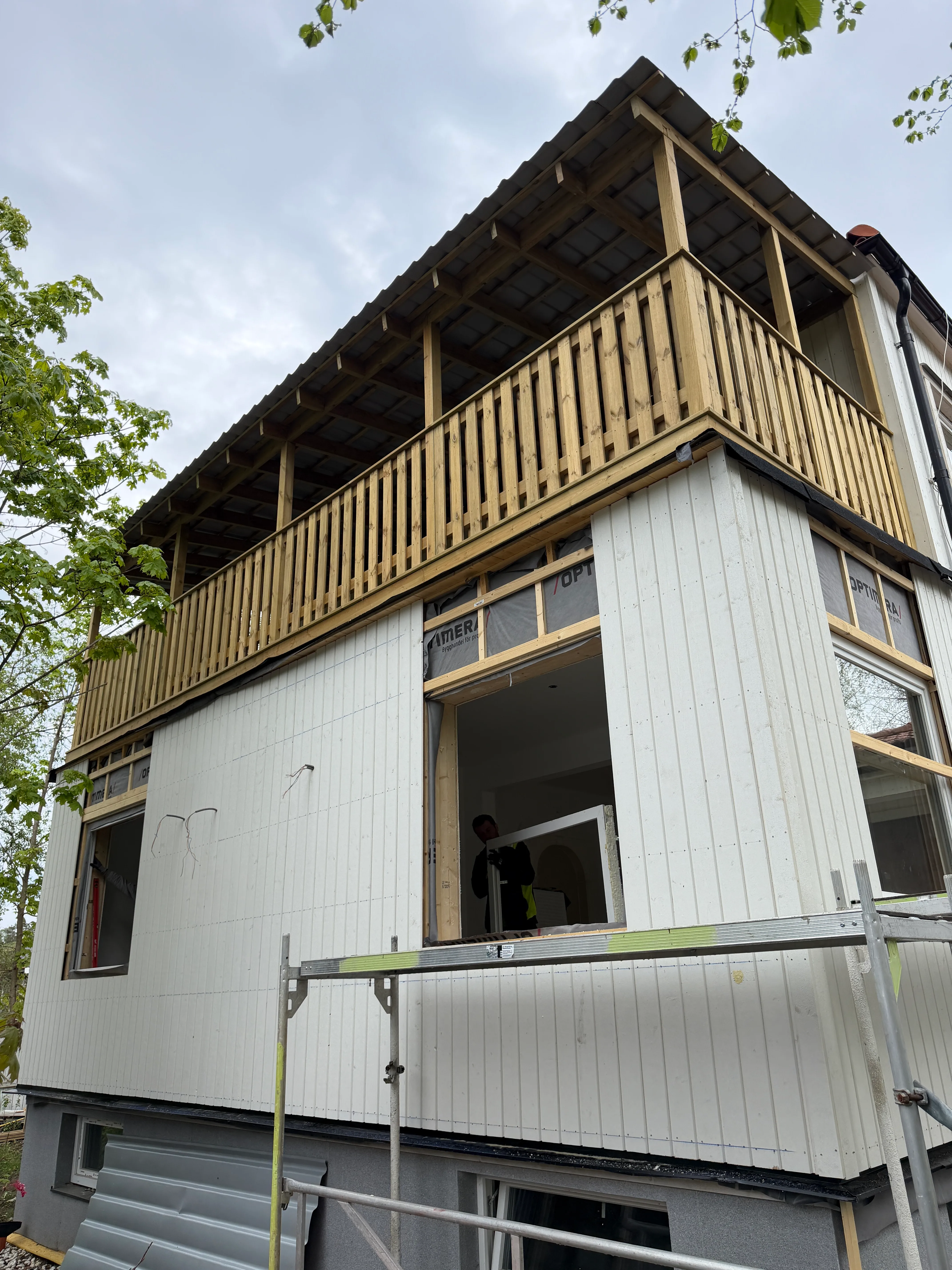 Modernt bostadshus med vit metallfasad och träbalkong