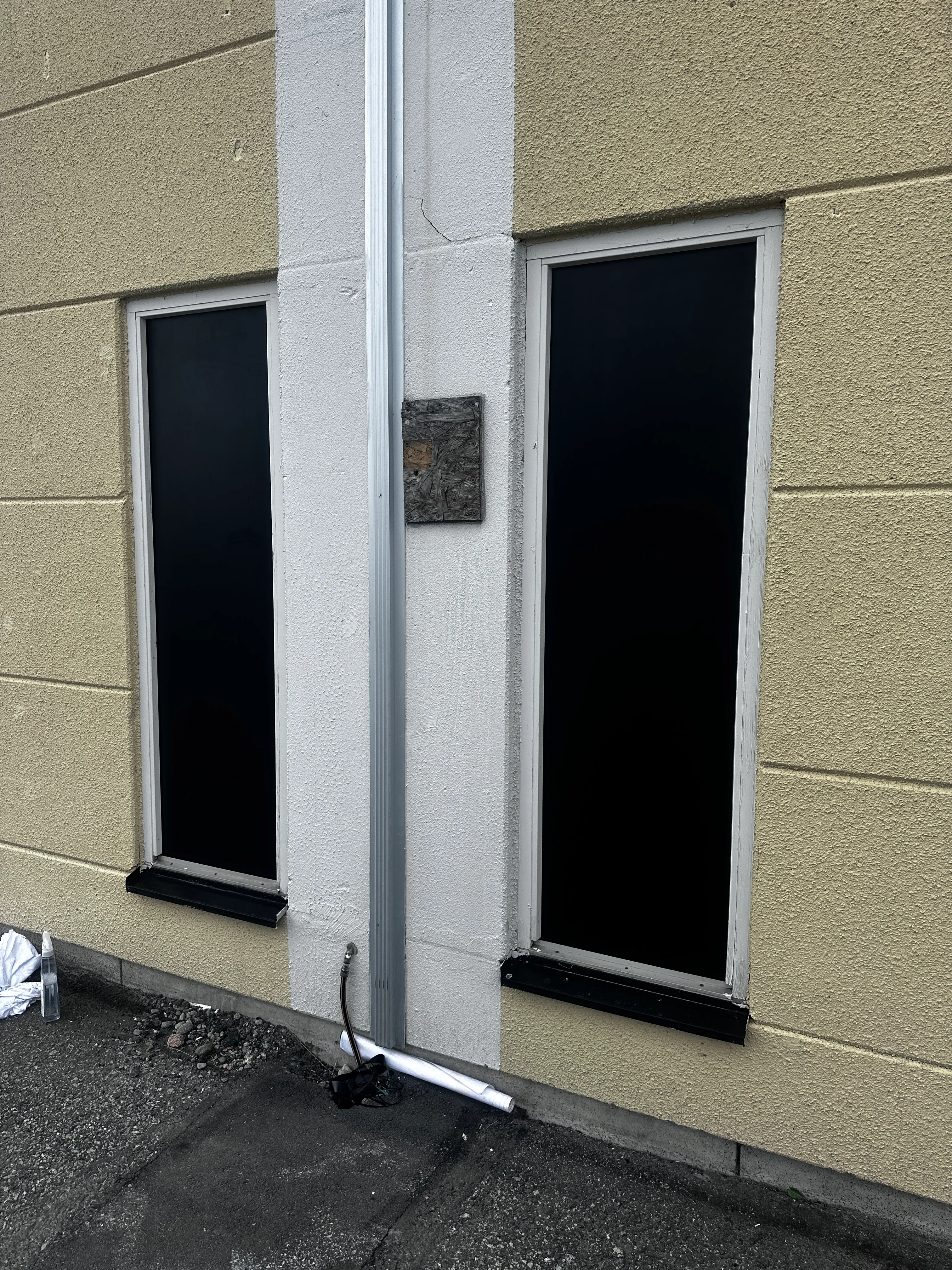 Stängda fönster med svart panel och vägg av ljus färg. Fokus på detaljer i byggnadsarbete