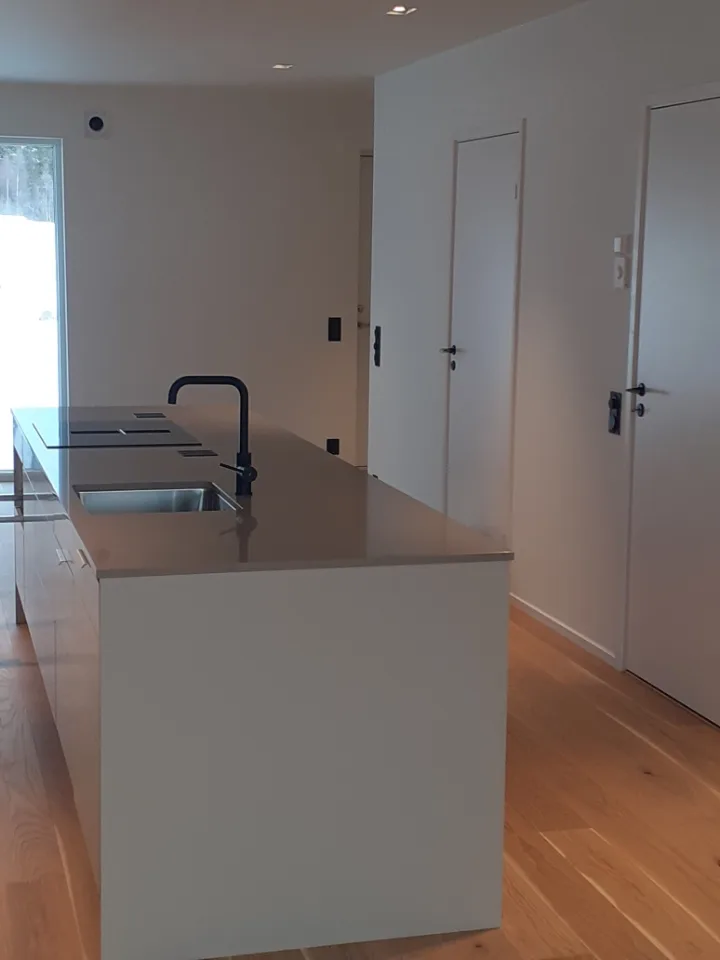 Modernt kök med en köksö och släta ytor i ljusa färger