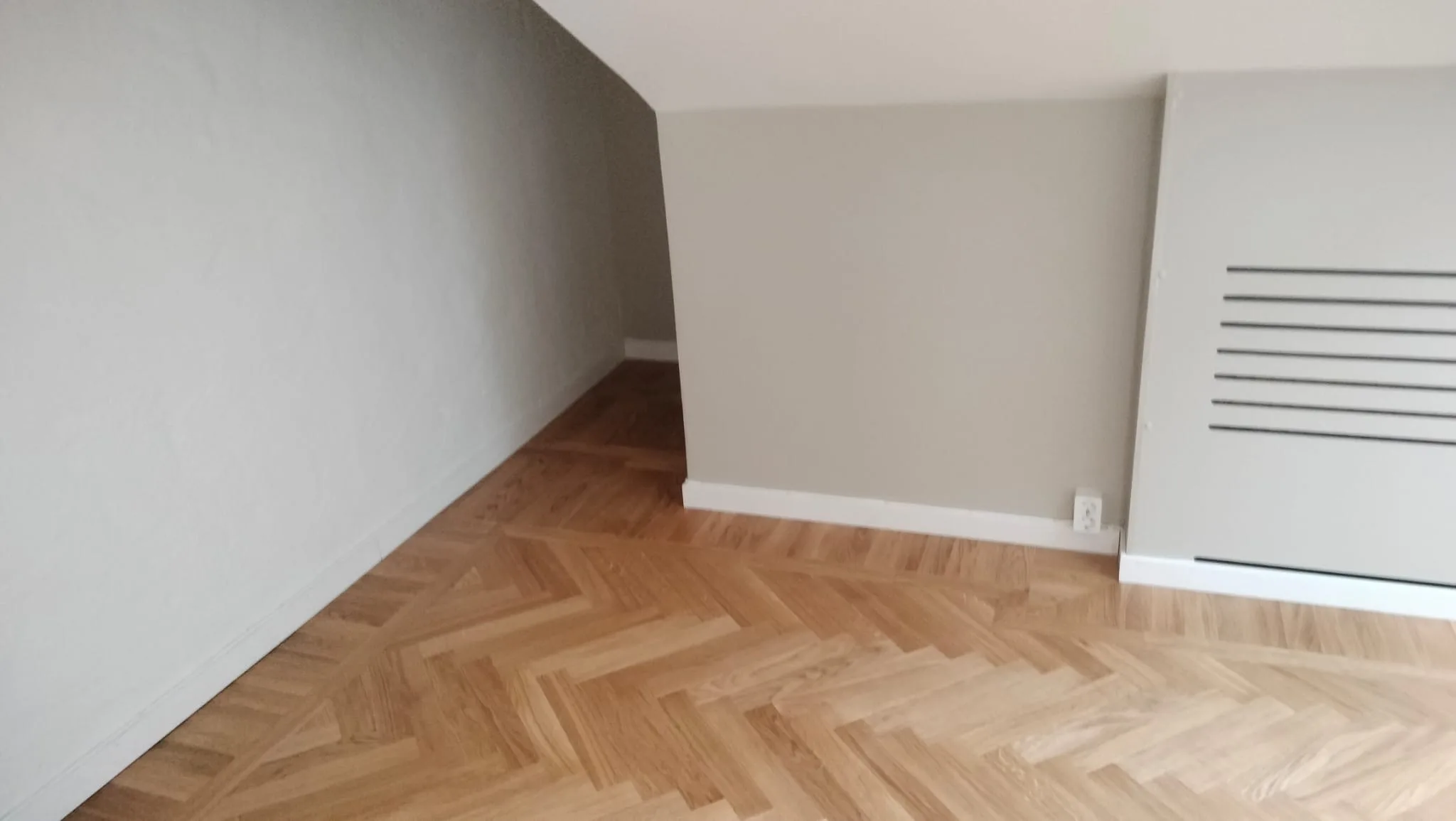 Renoverat rum med mönstrat trägolv och ljusa väggar