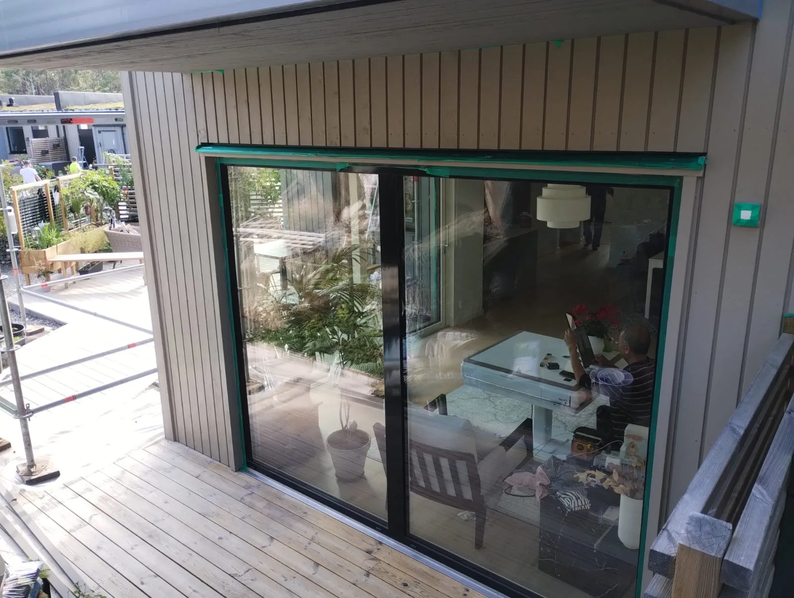 Modernt kubhus med gröna glasdörrar och terrass