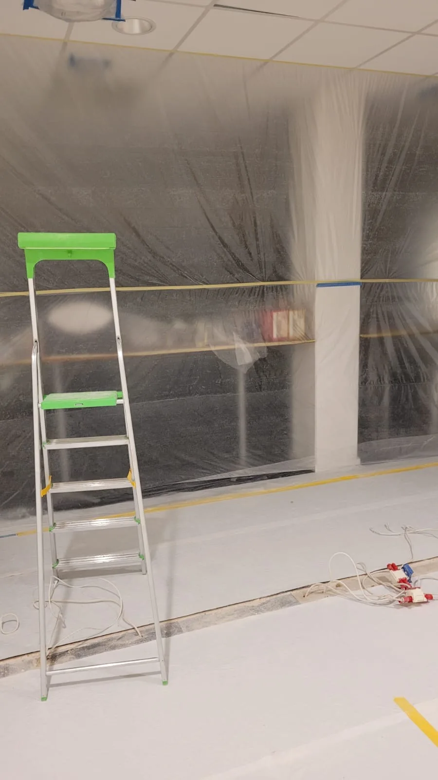 En stege framför en plastskyddad vägg i en byggarbetsplats för renovering