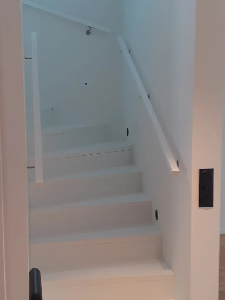 Vita trappor med räcken i en modern inredning, perfekt för husrenovering