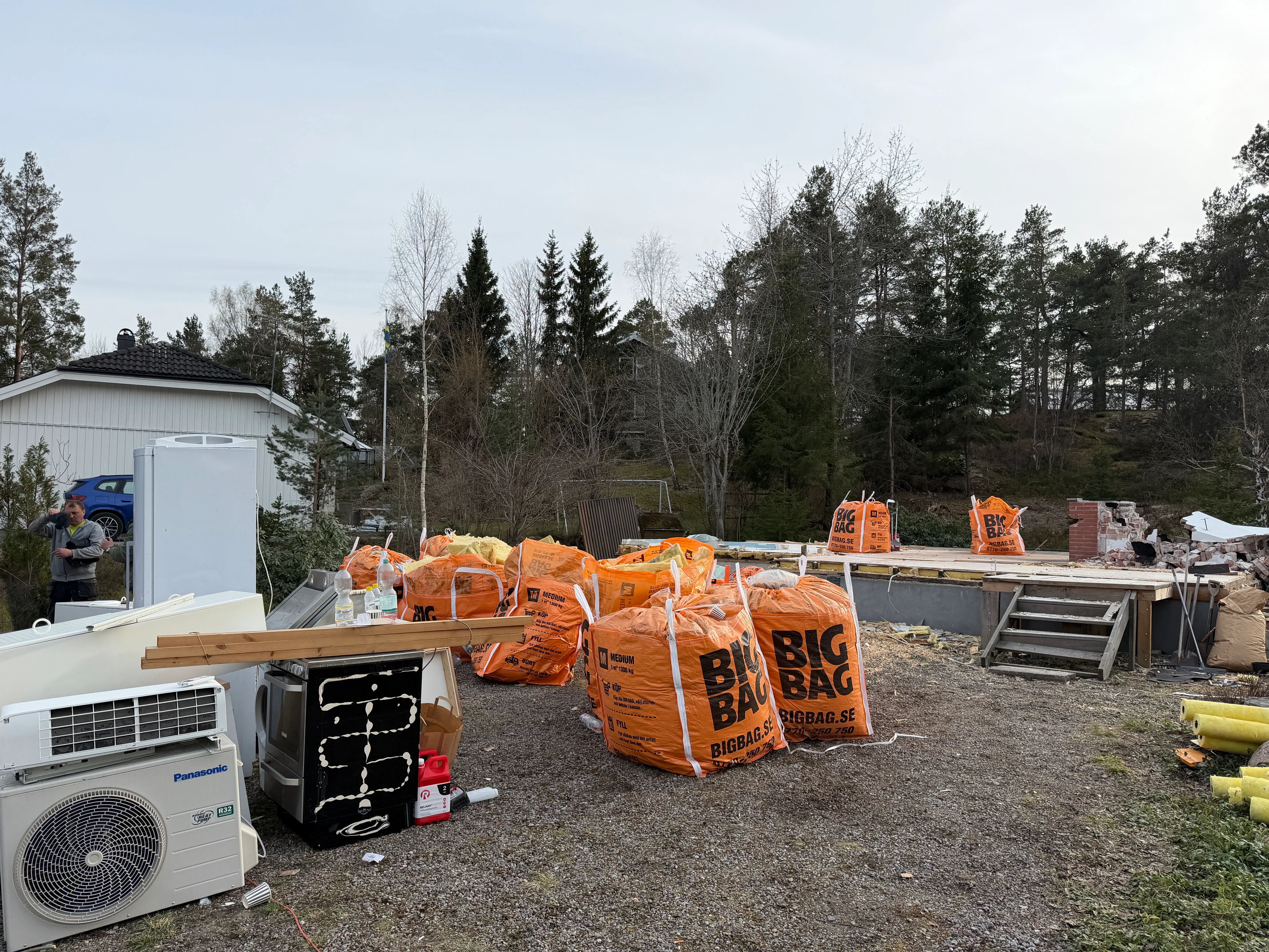 Byggarbetsplats med orangea big bag och material för renovering