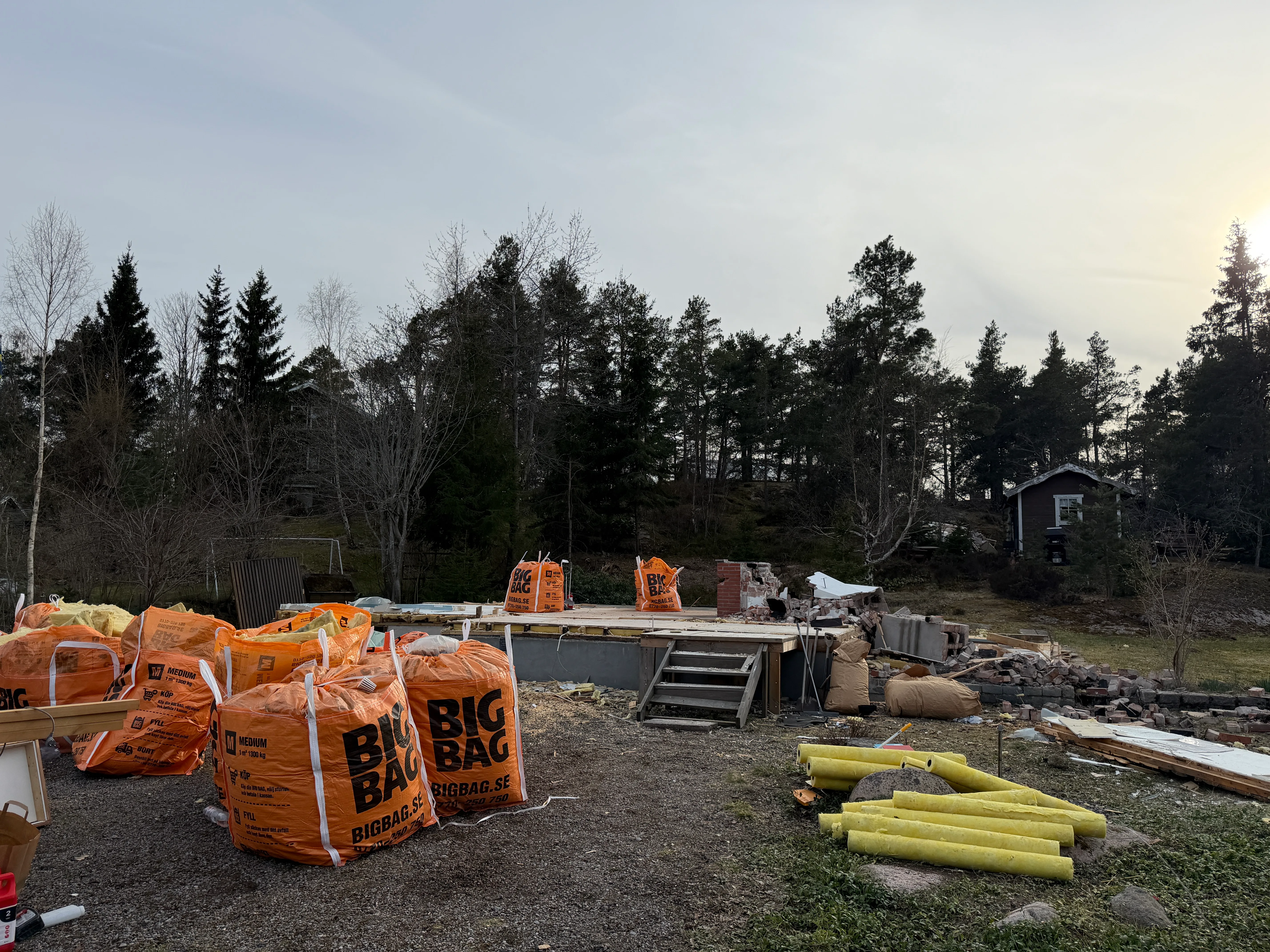 Byggarbetsplats med stora orangea säckar, fotar en pågående rivning