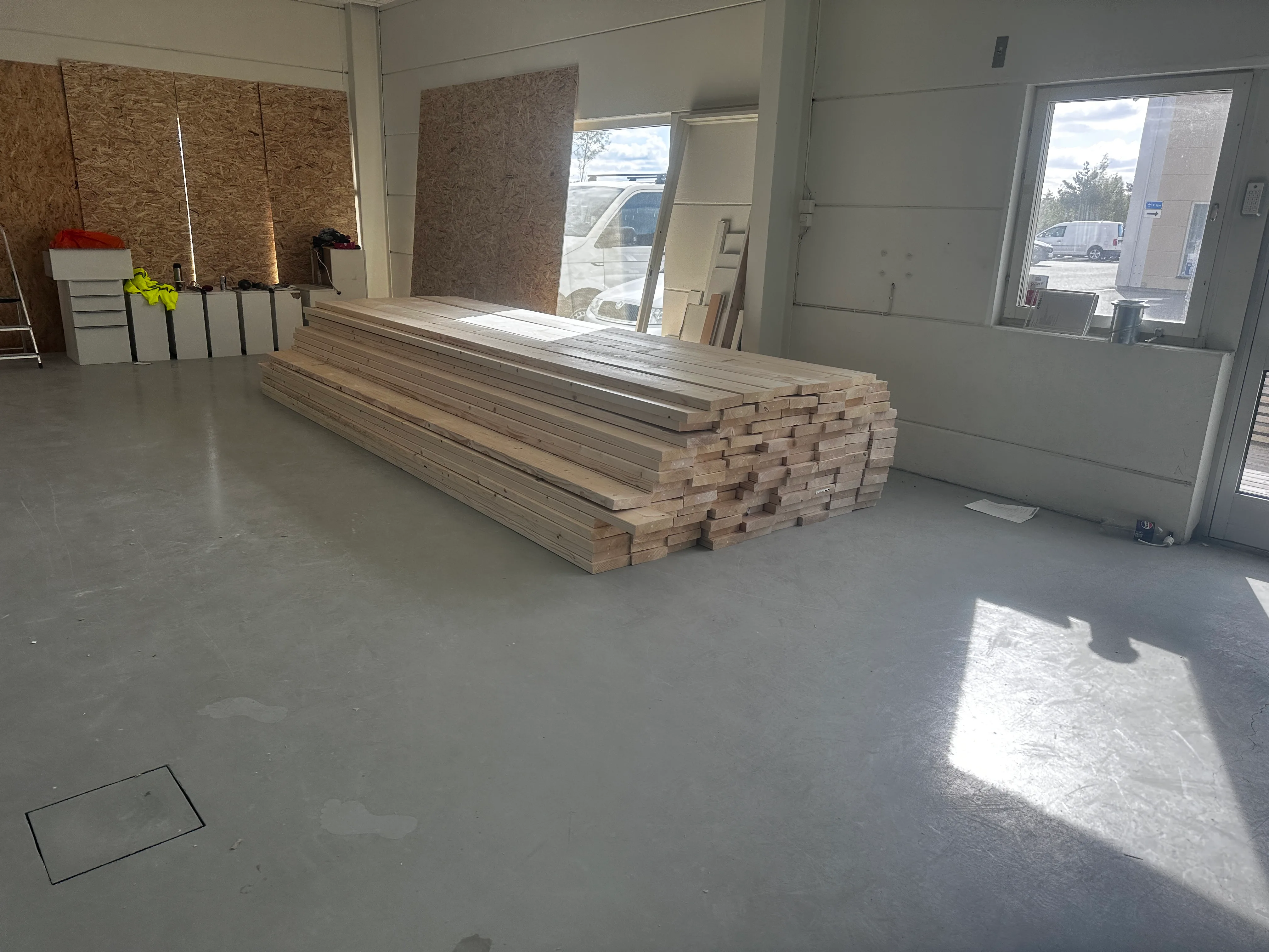Stapel av byggmaterial i en rymlig verkstad med gott ljus