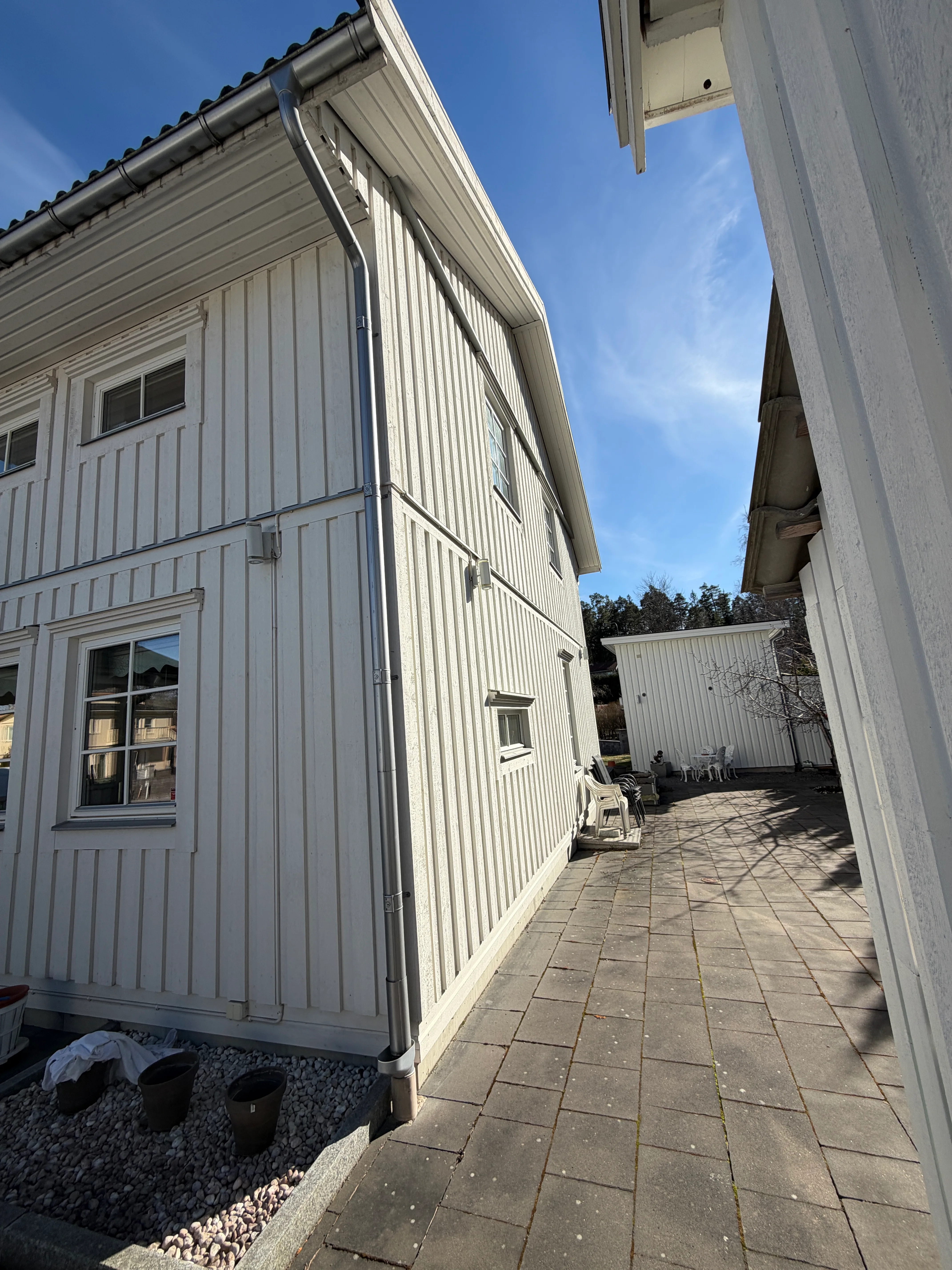 Nybyggnation av hus med vit träfasad och uppfart i soligt väder